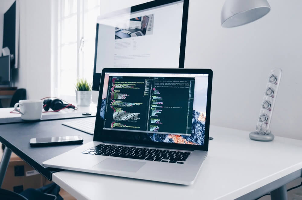 a coding screen is displayed on the laptop that placed in the working desk