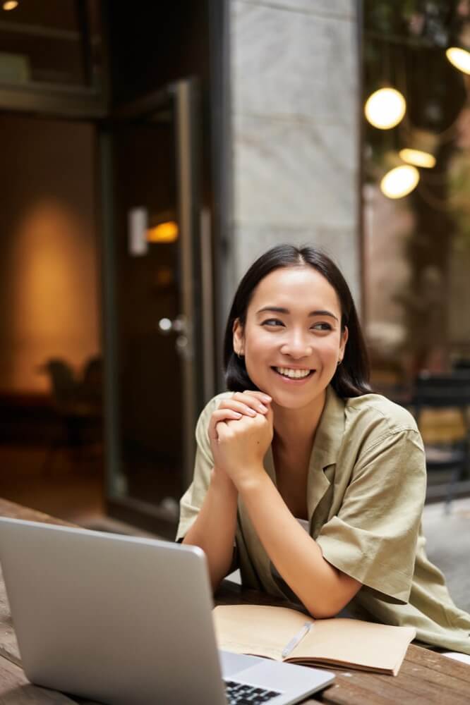 a girl is smilling next to her laptop