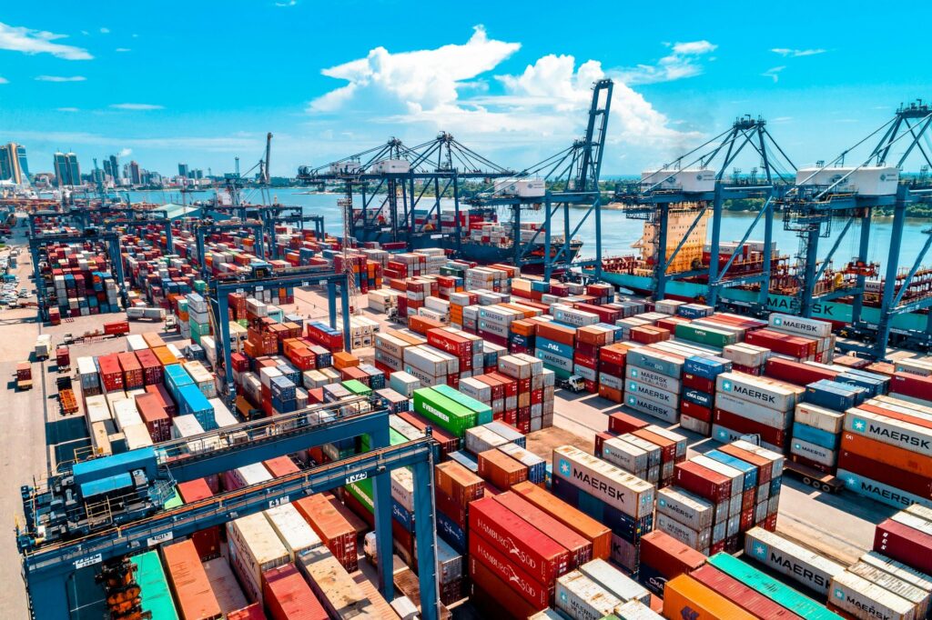 Stacked multi-coloured shipping containers organised in rows at a shipping port, used as a metaphor for the layered dependencies of a modern software supply chain