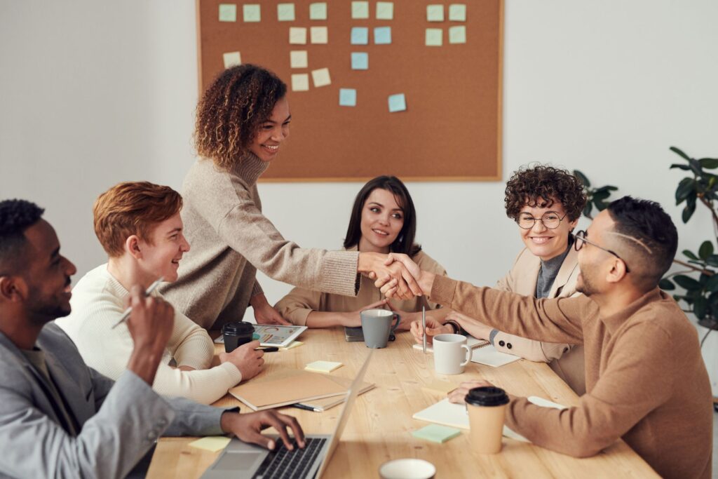 People at a meeting table, with two participants shaking hands.