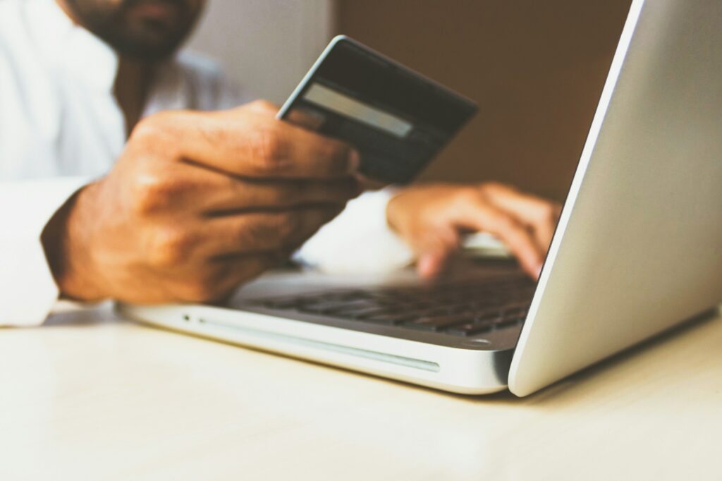 Person holding a payment card while using a laptop for an online purchase